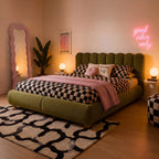 Olive velvet ottoman bed with curved headboard, checkered bedding, pillows.