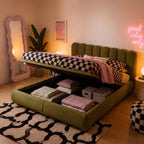 Olive velvet ottoman bed with arched headboard, checkered duvet, open storage bench.