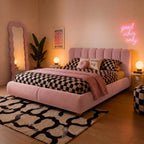 Pink tufted ottoman bed with checkered duvet and 'dream big' pillows.